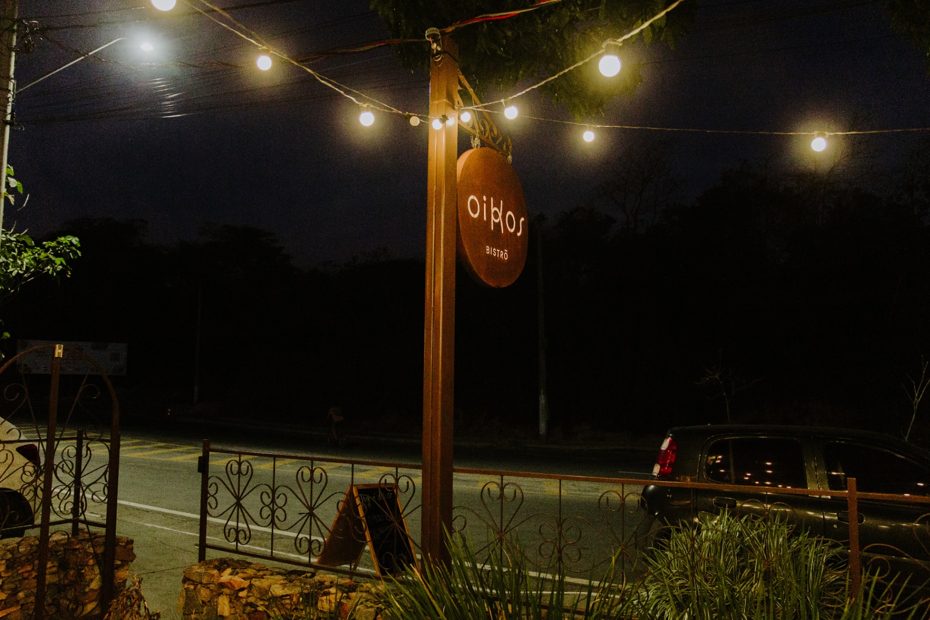 Placa iluminada do Oikos Bistro à noite